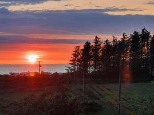 a sunset over the ocean with horses in a field at Cuillin View Apartment - Uk12529 in Arisaig