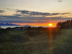 a sunset in a field with the sun in the sky at Cuillin View Apartment - Uk12529 in Arisaig