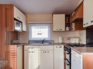 a small kitchen with white cabinets and a sink at Stay And Sea in Heysham