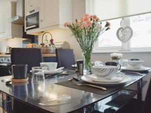een keuken met een tafel met borden en een vaas met bloemen bij Ingram Cottage in Bamburgh
