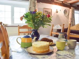a table with a cake and a vase with flowers at The Carthouse - Uk13184 in Cwm-Morgan