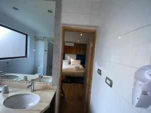 ein Badezimmer mit Waschbecken und ein Bett in einem Zimmer in der Unterkunft Hotel Lagoluz in Pucón + 35 Fotos