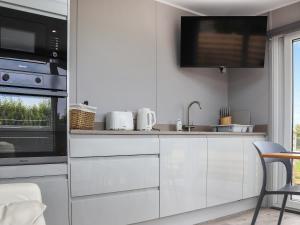 a kitchen with white cabinets and a microwave at Uk46570 - Awel Y Mor in Holyhead