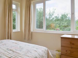 a bedroom with two windows and a bed and a dresser at Walters Cottage in Pilton +2 photos