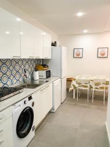 uma cozinha com uma máquina de lavar e secar roupa e uma mesa em Casas Sao Luis em Faro