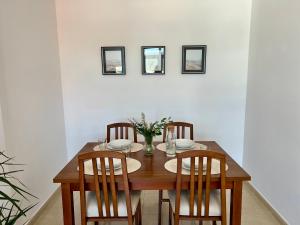 a dining room table with four chairs and a vase with flowers at Apartamento SOLPOR in Finisterre