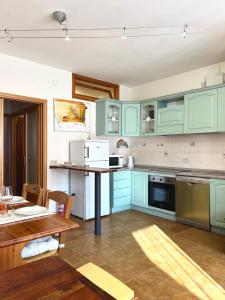 cocina con armarios de color verde menta y mesa en La Casa Del Mare, en Torre del Lago Puccini