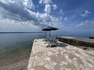 eine Gruppe von Stühlen unter einem Sonnenschirm auf einem Pier in der Unterkunft Apartments & Rooms Neno in Tribanj-Krušćica