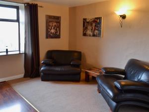 a living room with two leather chairs and a table at Wood Cottage in Whaley Bridge