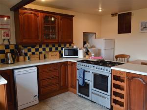 a kitchen with wooden cabinets and a stove top oven at Wood Cottage in Whaley Bridge +18 photos