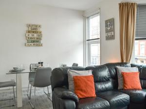 a living room with a black leather couch with orange pillows at Harbour View - Uk44164 in Bridlington