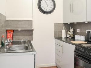 a kitchen with a sink and a clock on the wall at Harbour View - Uk44164 in Bridlington