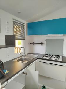 una cucina bianca con lavello e fornello di Mobilhome avec terrasse couverte à 800 m de la plage a Saint-Cast-le-Guildo