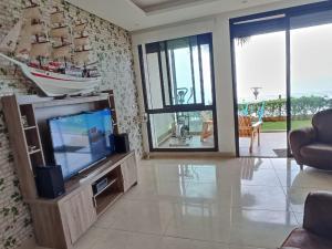 a living room with a tv and a boat on the wall at Appartement à Prestigia Plage des nations salé in Sale