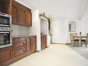 eine Küche mit Holzschränken und einem Tisch darin in der Unterkunft Willow Cottage in Hadston