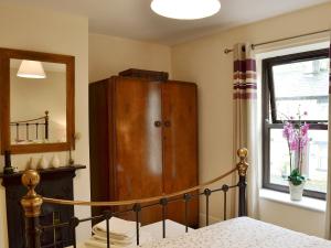 ein Schlafzimmer mit einem Holzschrank neben einem Fenster in der Unterkunft Park View Cottage in Old Glossop