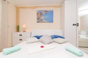 a bedroom with a white bed with blue pillows at Family-friendly apartments with swimming pool Vodovadja, Dubrovnik - 24632 in Dubravka +10 photos