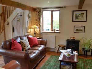 ein Wohnzimmer mit einer Ledercouch und einem Tisch in der Unterkunft Bryn Dedwydd Cottage in Llanferres