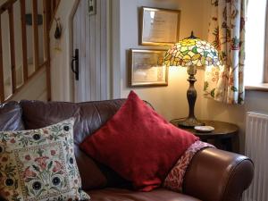 eine braune Ledercouch mit einer Lampe auf einem Tisch in der Unterkunft Bryn Dedwydd Cottage in Llanferres