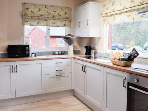 a kitchen with white cabinets and a sink and a window at Pheasant Lodge in Staithes
