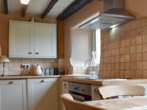 une cuisine avec des armoires blanches et une table avec des chaises dans l'établissement Thorn Cottage, à Spark Bridge