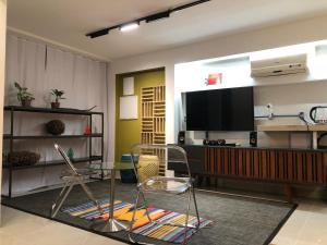 a living room with a television and a table and chairs at Studio equipado e decorado no Centro Balneário Camboriú in Balneário Camboriú