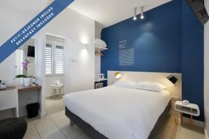 a bedroom with a large bed and a blue wall at Hôtel Les Voiles in Toulon