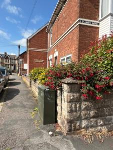 a brick building with flowers on the side of a street at St Anne's Road Guest House in Exeter