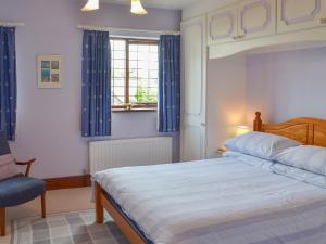 a bedroom with a bed and a window with blue curtains at Kay's Cottage in Buckfastleigh