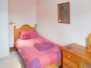 a bedroom with a bed and a wooden dresser at Kay's Cottage in Buckfastleigh +6 photos