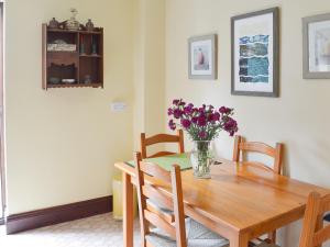 a dining room table with a vase of flowers on it at Kay's Cottage in Buckfastleigh