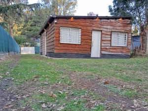 a log cabin with a white door in a yard at Cabaña Entre Arboles in Tandil