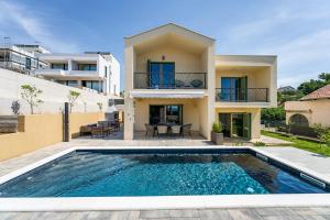 a villa with a swimming pool in front of a house at Villa Franka - holiday home with a private pool in Sveti Filip i Jakov