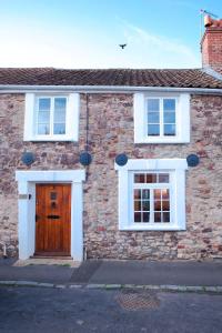 ein Backsteinhaus mit einer Holztür und zwei Fenstern in der Unterkunft Historic Cottage & Garden nr Quantock Hills in Nether Stowey