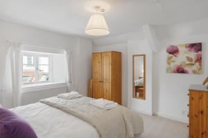 ein weißes Schlafzimmer mit einem großen Bett und einem Fenster in der Unterkunft Historic Cottage & Garden nr Quantock Hills in Nether Stowey + 33 Fotos