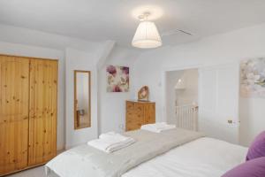 ein Schlafzimmer mit einem großen weißen Bett mit Handtüchern darauf in der Unterkunft Historic Cottage & Garden nr Quantock Hills in Nether Stowey