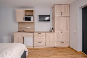 a kitchen with wooden cabinets and a bed in a room at Freda Self Check-in in Nida
