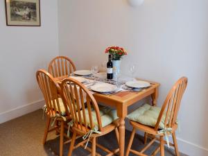 a wooden table with four chairs and a bottle of wine at The Cottage in Broadstairs