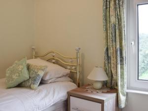 a bedroom with a bed and a table with a lamp at Cobb's Cottage in Grosmont