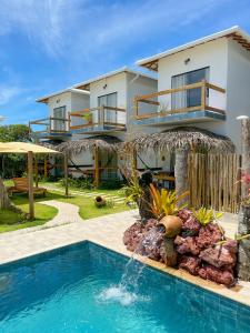 a villa with a swimming pool in front of a house at POUSADA CAJU DO MATO in Prado