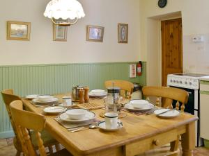 een houten tafel met stoelen en borden erop bij Thurston View in Coniston