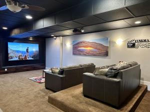 Una habitación con dos sofás de cuero y una pantalla grande. en Exclusive Retreats 6 Bed 6 Bath with Private Pool, en Moab