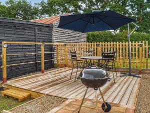 a grill and an umbrella on a wooden deck at Newlyn Cottage in Pluckley