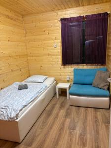 a bedroom with a bed and a blue couch at Faház - Nyaraló a Tiszánál in Tiszacsege
