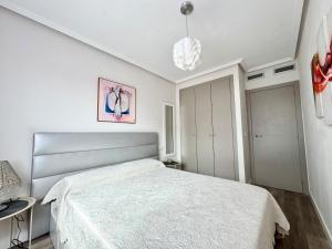 a white bedroom with a bed and a chandelier at Vacation Apartment in Els Poblets