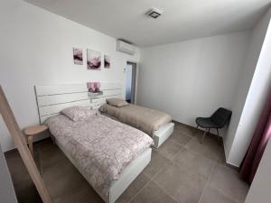 a small bedroom with two beds and a chair at Nîmes Downtown Apartment in Nîmes