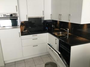 a kitchen with white cabinets and black counter tops at Aan zee in Nieuwpoort in Nieuwpoort