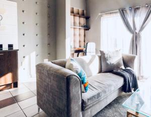 Una sala de estar con un sofá y una ventana. en Dainfern Fourways apartment offering privacy and a lavishly expansive balcony views, en Sandton 43 fotos más