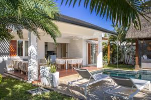 a patio with a table and chairs next to a swimming pool at Comfortable villa with private pool in Grand-Baie