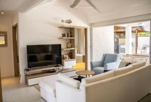 a living room with white furniture and a flat screen tv at Comfortable villa with private pool in Grand-Baie